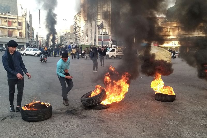 FILE PHOTO: Demonstrators stand near burning tires during a protest