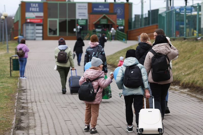 Ukrainian refugees walk towards border crossing from Poland to Ukraine,