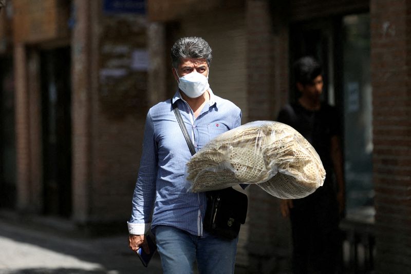 FILE PHOTO: An Iranian man holds stacks of bread as