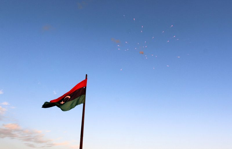 FILE PHOTO: Libyan flag flies as fireworks explode during celebrations