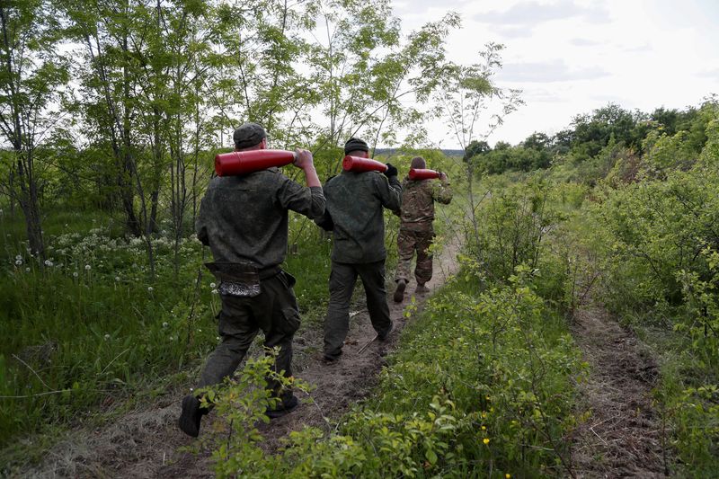 FILE PHOTO: Service members of pro-Russian troops carry leaflet shells