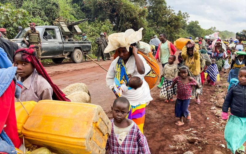 Congolese civilians carry their belongings as they flee near the